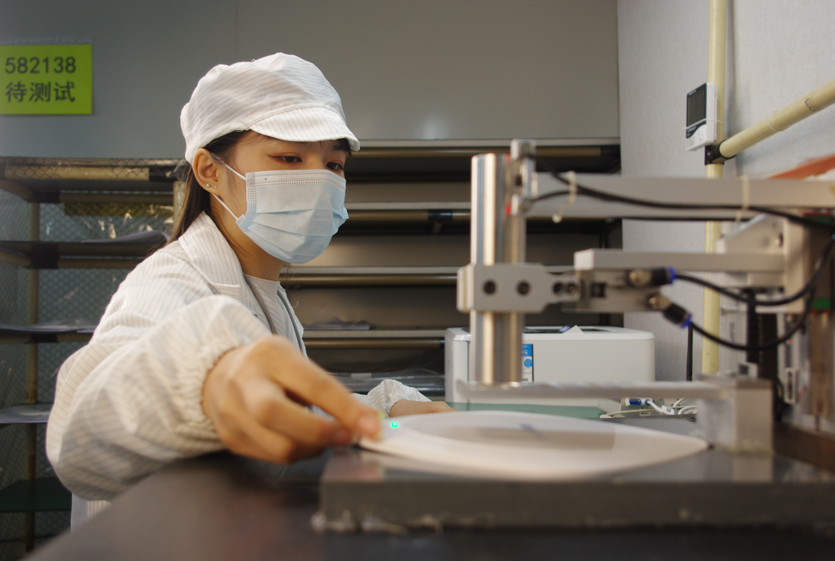 SMT engineers reviewing a populated circuit board at an inspection station on the production floor
